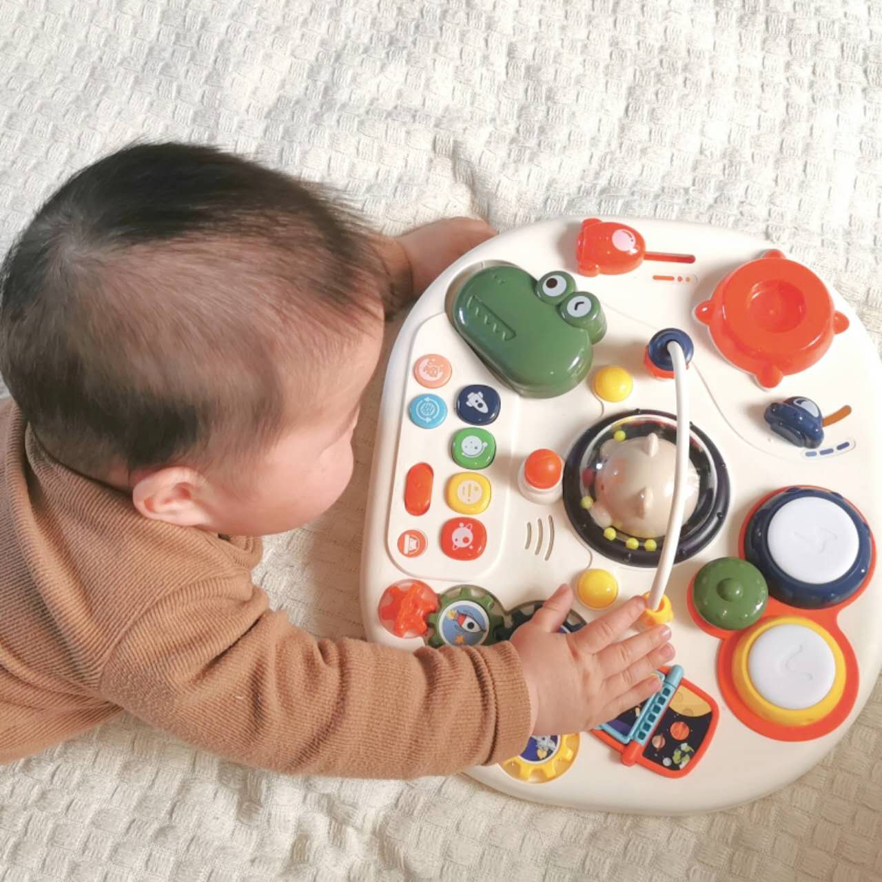 Een baby speelt met de motoriekactiviteit op de speeltafel